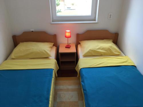 two beds in a room with a lamp on a night stand at Apartmani Marija Klimno A in Klimno