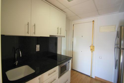 a kitchen with white cabinets and a black counter top at Apartamento CasaTuris en el corazon de Alicante A118 in Alicante