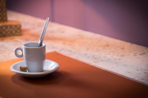 a cup on a table with a spoon in it at Hotel restaurant Spa Disini Montpellier Est, The Originals Relais in Castries