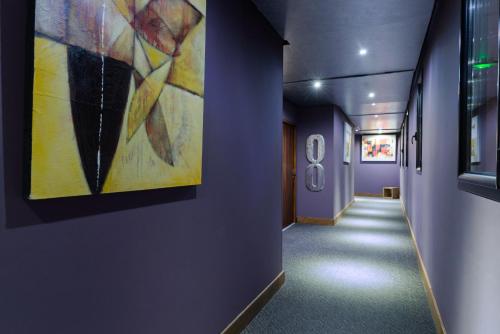 a hallway in a building with a painting on the wall at Hotel restaurant Spa Disini Montpellier Est, The Originals Relais in Castries