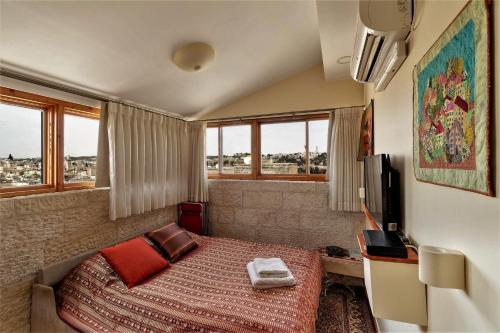 a bedroom with a bed and a tv and windows at Into Jerusalem heart in Jerusalem