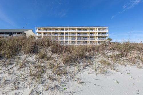 a building on top of a beach with grass and sand at Windy Shores II in Myrtle Beach