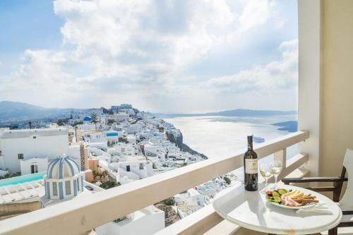 a table with a glass of wine on a balcony with a view at Villa Ilias in Firostefani