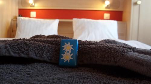 a bed with a brown blanket and a blue book on it at Hotel Europa in Saas-Fee