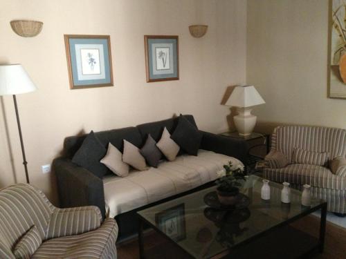 a living room with a couch and two chairs and a table at Quartos City Apartments Carmona in Carmona