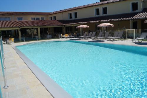a large blue swimming pool with chairs and umbrellas at Hotel Restaurant La Martiniere in Montélier