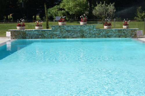 a large blue swimming pool with a stone wall at Hotel Restaurant La Martiniere in Montélier