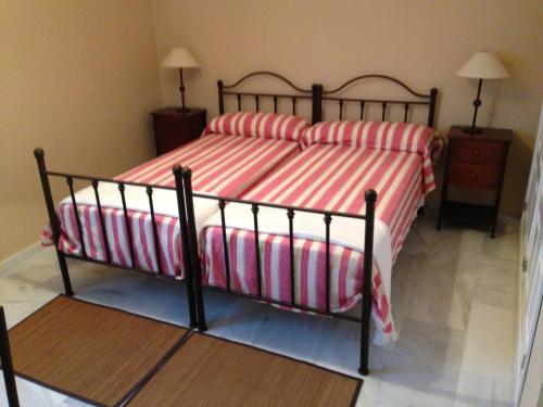 a bedroom with a bed with red and white striped sheets at Quartos City Apartments Carmona in Carmona