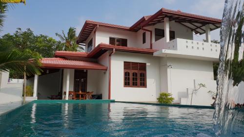 a villa with a swimming pool in front of a house at Emildale Villa in Wadduwa