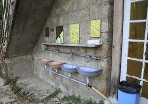 uma parede de pedra com três lavatórios em Auberge de Jeunesse Chez Mc Donald em Zevaco
