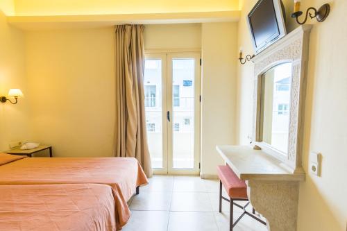 a hotel room with a bed and a desk and a window at Pela Sofia in Stalís