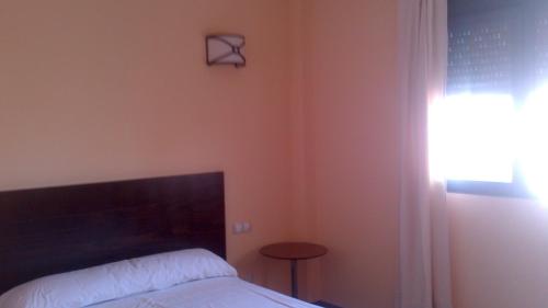 a bedroom with a bed and a table and a clock on the wall at Posada La Casona de Valbuena in Valbuena de Duero