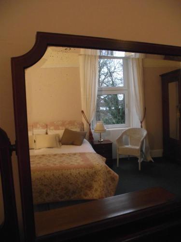 a mirror reflecting a bedroom with a bed and a window at The Old Rectory in Annan