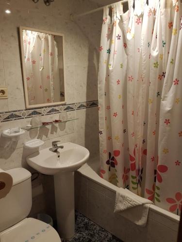 a bathroom with a sink and a toilet and a shower curtain at Pension los Verdiales in La Herradura