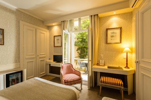 um quarto com uma cama, uma cadeira e uma janela em Hôtel du Parc em Montpellier