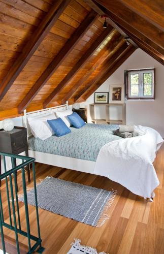 a bedroom with a large bed with blue pillows at Casa da Manta - Palheiro in Fajã da Ovelha