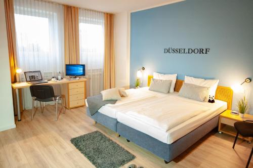 a bedroom with a large bed and a desk with a computer at KEMPE Komfort Hotel in Düsseldorf