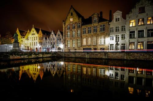 a city lit up at night with reflections in the water at Boutique Hotel Sablon by CW Hotel Collection in Bruges