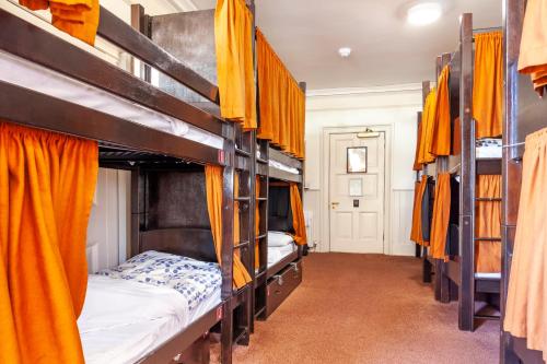 a room with four bunk beds with orange curtains at Palmers Lodge Swiss Cottage in London