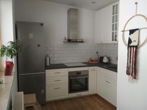 cocina con armarios blancos y nevera de acero inoxidable en Apartament w Dolinie Popradu, en Piwniczna-Zdrój