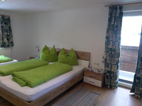 - une chambre avec 2 lits et des oreillers verts dans l'établissement Haus Sonnenalm, à Sankt Sigmund im Sellrain