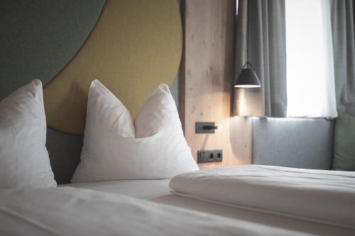 a bedroom with a bed with white pillows and a window at Garberhof Dolomit Family in Rasùn di Sotto