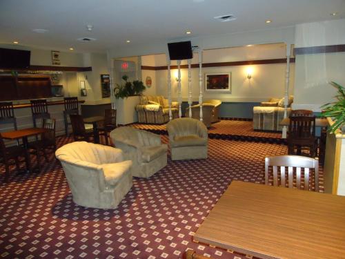 a waiting room with chairs and tables and a bar at Ramada by Wyndham Trenton in Trenton