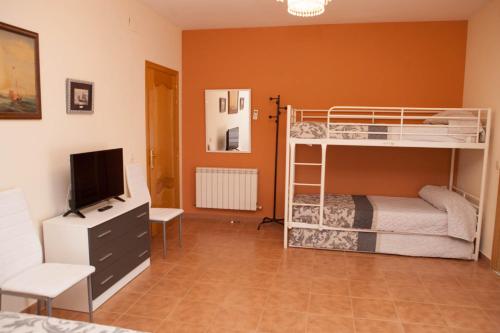 a bedroom with two bunk beds and a television at La Rosaleda de Orgaz in Orgaz