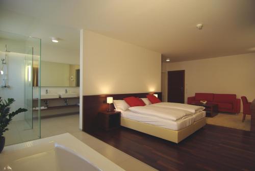 a bedroom with a bed and a bathroom with a tub at Hotel & Restaurant Christkindlwirt in Steyr