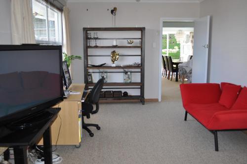 a living room with a television and a red couch at 16 Havelock in New Plymouth