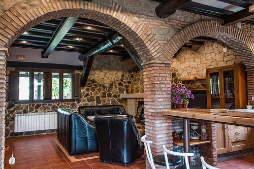 a kitchen with a stone wall with chairs and a table at Apartamentos Rurales Fuente Chiquita in Hervás