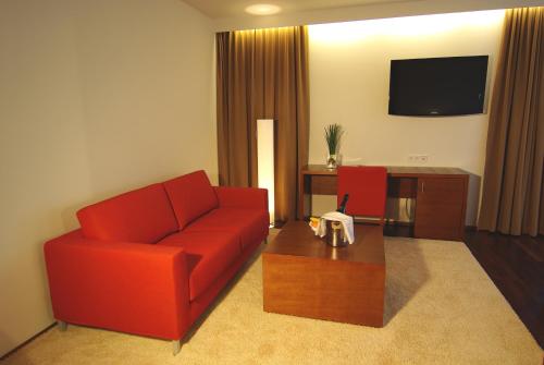 a living room with a red couch and a coffee table at Hotel & Restaurant Christkindlwirt in Steyr