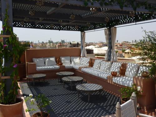 a patio with couches and tables on a roof at Dar Andamaure in Marrakech