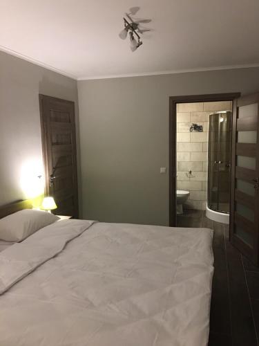 a bedroom with a white bed and a bathroom at 7Days in Hadyach