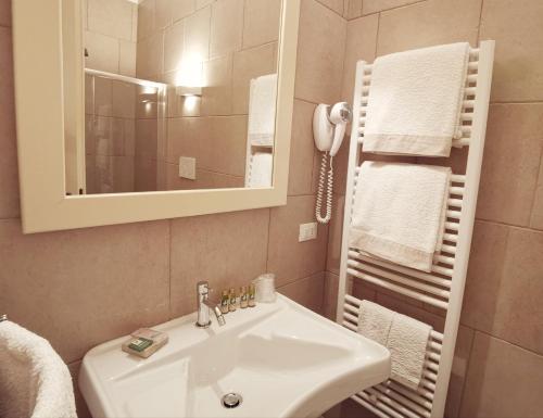 a bathroom with a sink and a mirror and towels at Le Nicchie Guest House in Lucera