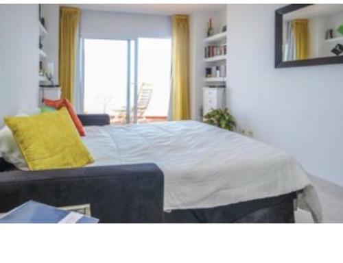 ein Schlafzimmer mit einem großen Bett und einem gelben Kissen in der Unterkunft Rosa de los Vientos in Málaga