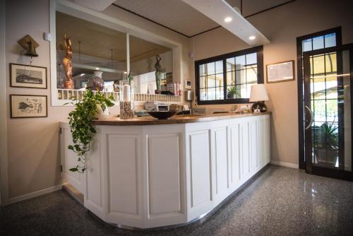 a kitchen with white cabinets and a large mirror at Hotel Jesolo Sand in Lido di Jesolo