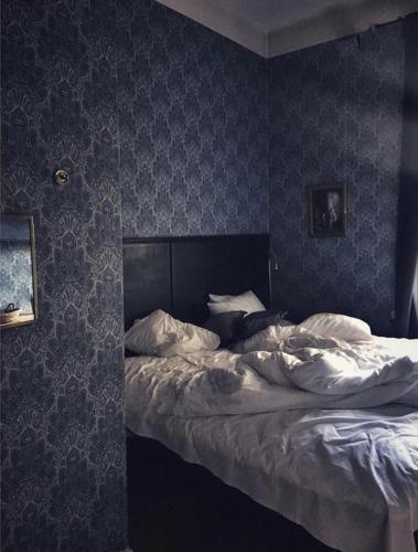 a bed in a bedroom with blue wallpaper at Morris Hotel in Örebro
