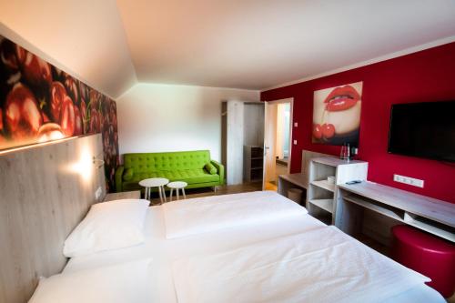 a bedroom with two beds and a green couch at Wallner - Hotel & Wirt in Arnoldstein