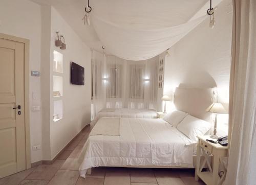 a white bedroom with a white bed and a desk at Le Nicchie Guest House in Lucera