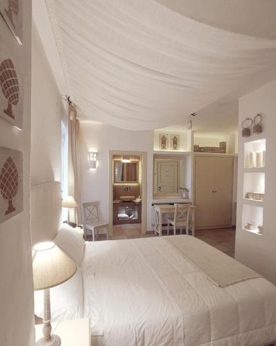 a bedroom with a white bed and a kitchen at Le Nicchie Guest House in Lucera