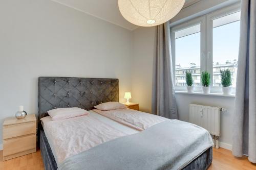 a bedroom with a large bed with a large window at Apartament Stylowy in Gdynia