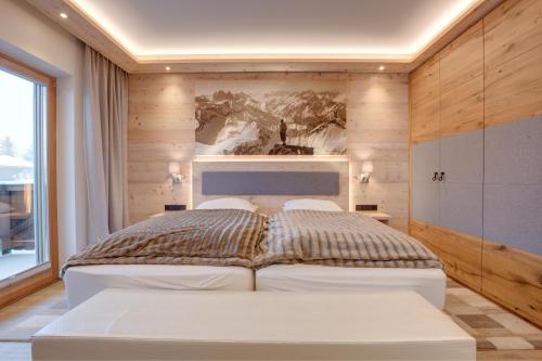 a bedroom with a bed and two white chairs at Villa Mountainview - Kirchberg bei Kitzbühel, Sauna, Kamin, nicht weit zu den Skiliften in Kirchberg in Tirol