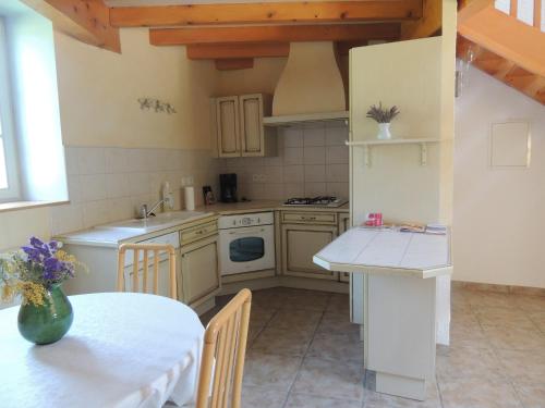 uma cozinha com uma mesa e um balcão branco em La Ferme des Buis em Mercurol
