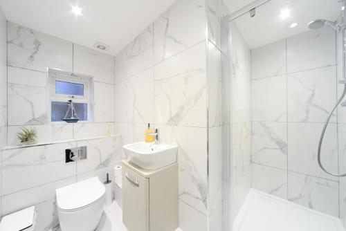 a white bathroom with a shower and a toilet and a sink at Amazing Apartment near Bournemouth, Poole & Sandbanks - WiFi & Smart TV - Newly Renovated! Great Location! in Poole