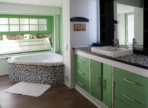 a bathroom with a tub and a sink at Tranquil Gem - lush garden view & solar energy! in Plettenberg Bay