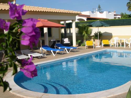 a swimming pool with chairs and umbrellas next to a house at VILLA EBER - independent 1 & 2 bedroom apartments, pool, air con, fast Wi-Fi, near old town of Albufeira and beaches in Albufeira