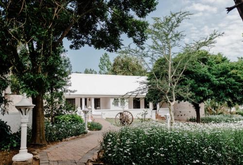 a white house with trees and white flowers at De Opstal Country Lodge in Oudtshoorn
