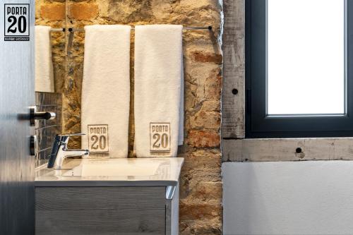 a bathroom with a sink and towels on a wall at Porta 20 Boutique Guesthouse in Leiria