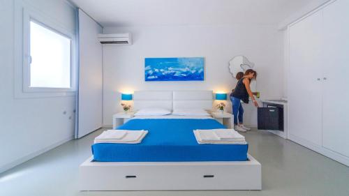 una mujer parada en una habitación blanca con una cama en Hotel Beach Salento en Marina di Pescoluse